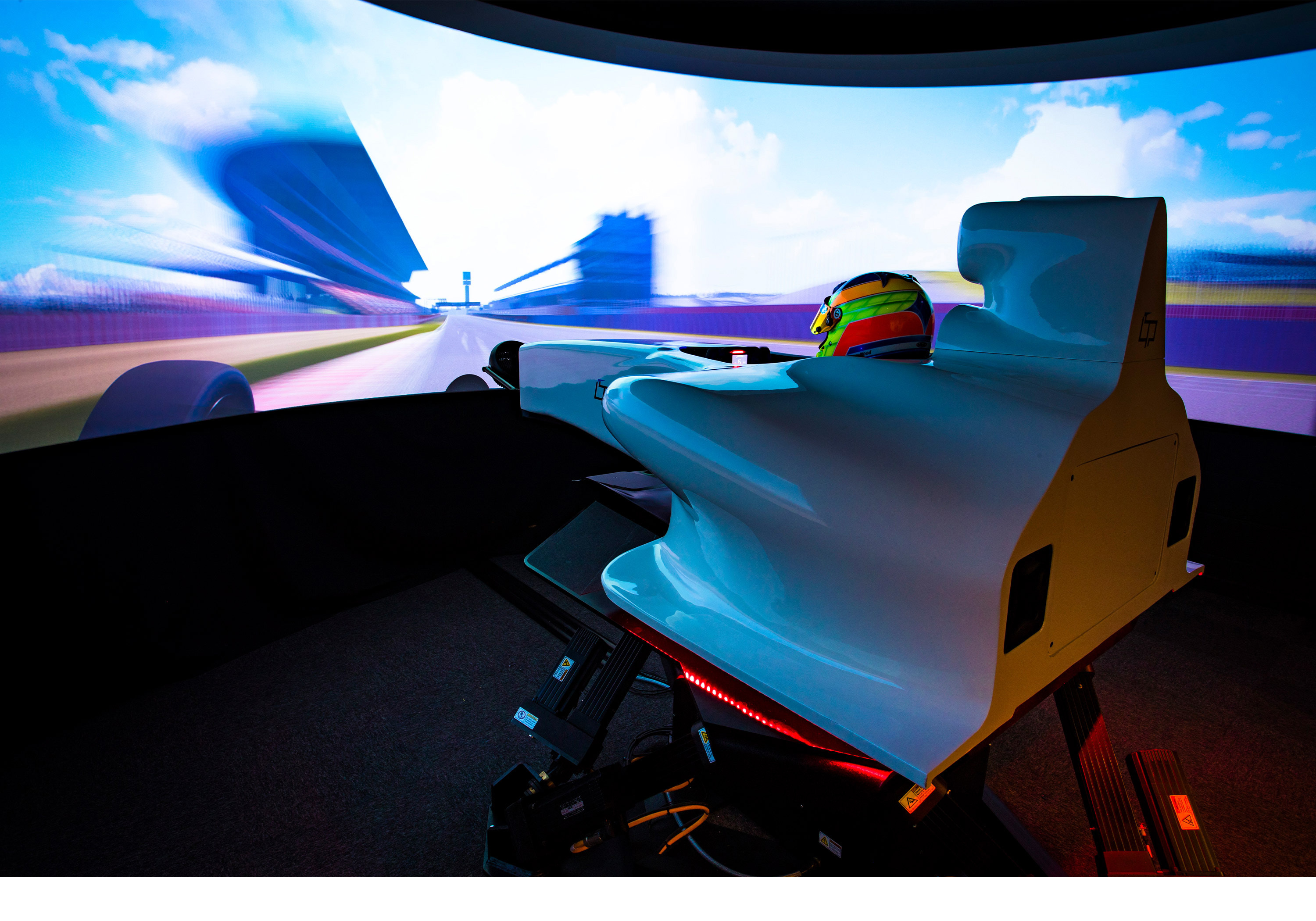 A racing driver sits in a driving simulator with technology by Moog